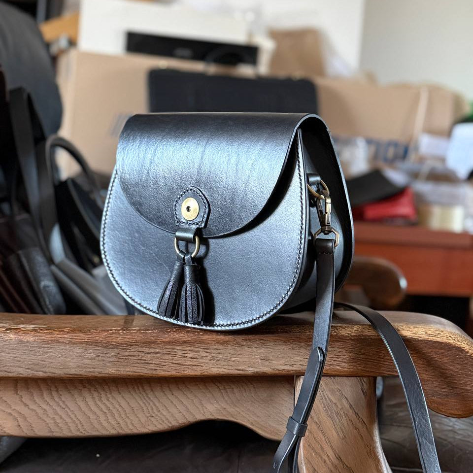 Black leather satchel front view with tassel detail  