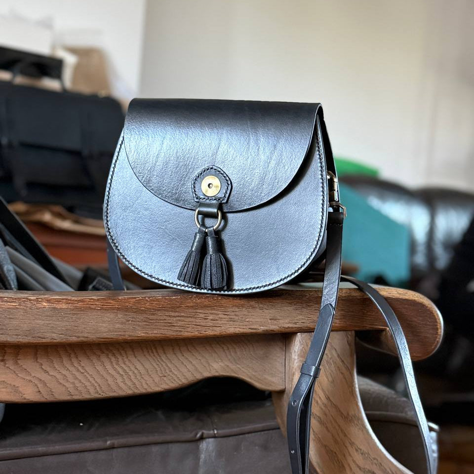 Black handmade leather bag photographed in workshop  